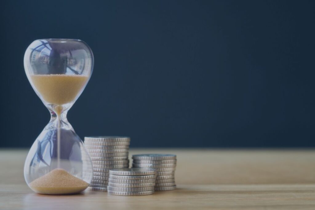 Klepsydra i monety symbolizujące oszczędność czasu, jaką otrzymuje klient dzięki współpracy z wirtualną asystentką - Aleksandra Łabaj